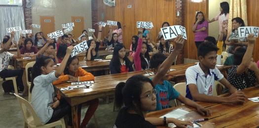 Students raise signs during the research quiz competition portion of the workshop.