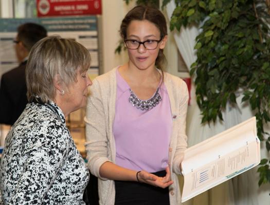 Aria describes her research with a judge at the 2016 Broadcom MASTERS Project Showcase.