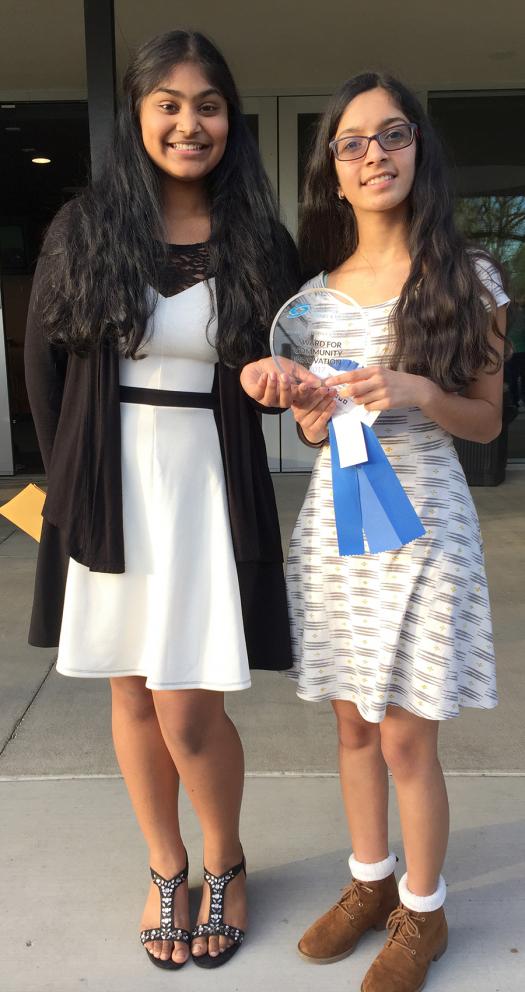 Akshara and Suditi hold up the Community Innovation Award they received from the Society for their research on natural greywater filters.