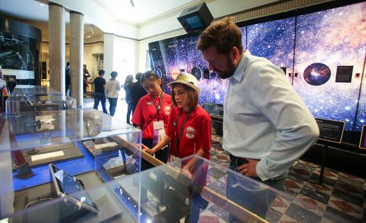 Pei-Yun Chang, from Taiwan, and Giancarlo Villaverde, from Puerto Rico, learn about the progress of telescopes alongside David Garrett, a Distinguished Engineer at Broadcom at the Griffith Observatory.