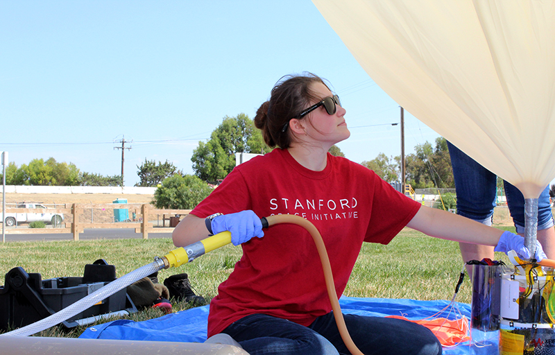 Paige Brown fills helium into the neck of a latex balloon attached to ValBal.