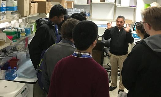 Learoy Saligan explaining his lab's research to the finalists. 