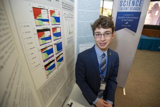 Sam stands with his project board during the Regeneron STS 2019 Public Showcase
