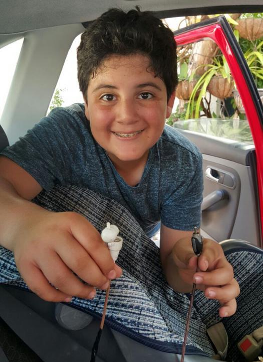 Joaquin holds up his car seat alarm system inside a car.