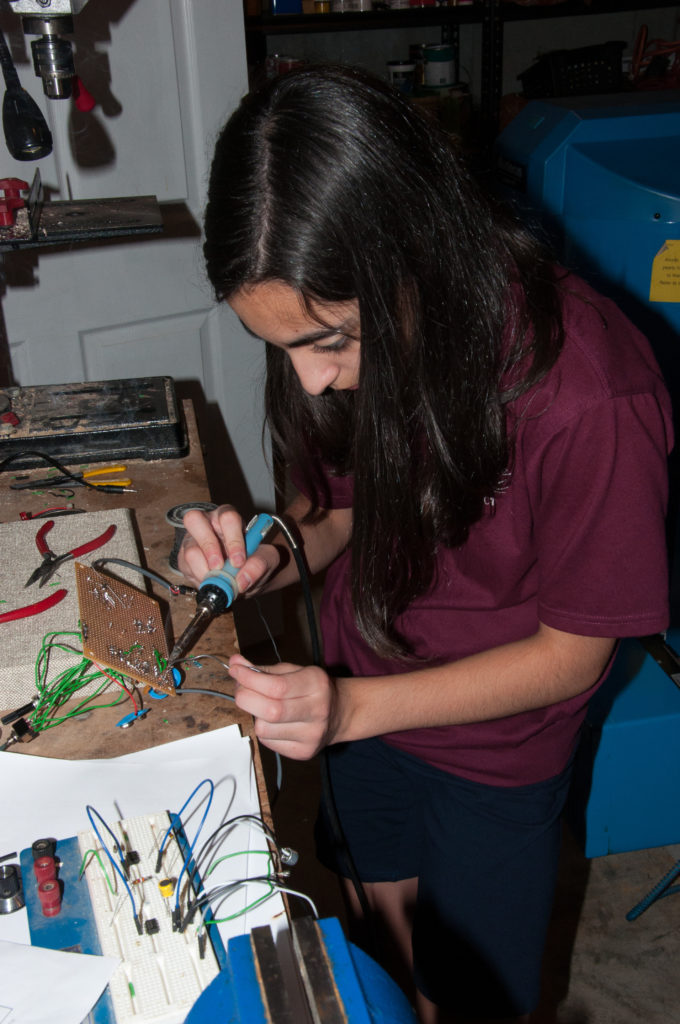 Payton soldering the inner workings of her invention.