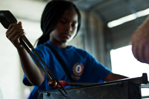 Student of SAFE Alternative program shaping a molten hot piece of glass