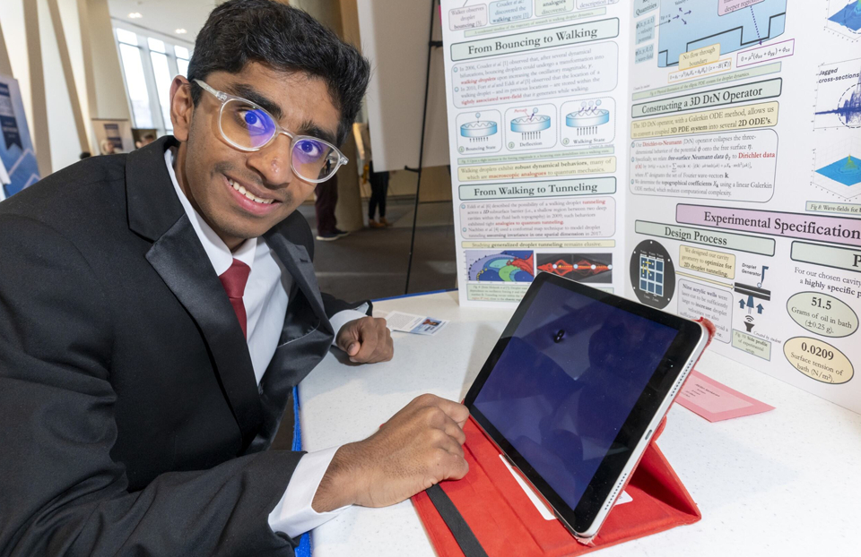 Regeneron STS 2025 finalist Akilan Sankaran posing with his iPad and trifold at public day.