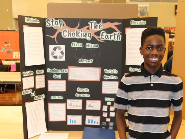 student standing in front of project board