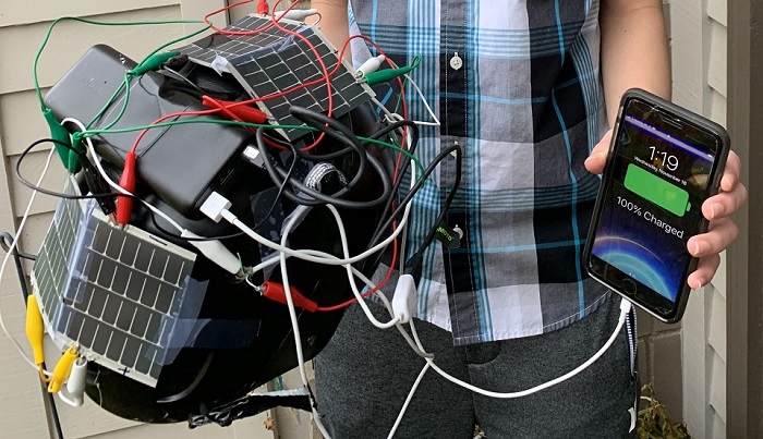 student holding helmet covered in solar panels