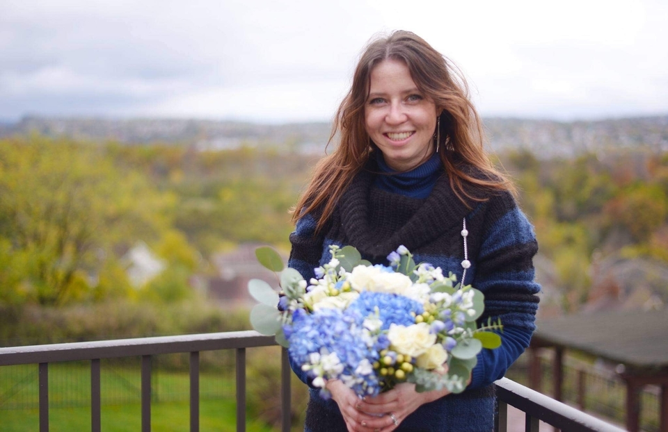 Alina Bengert-Lombardi standing outdoors, holding a bouquet of flowers