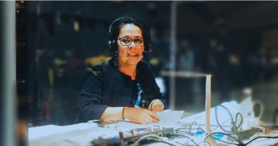 Edna Santizo smiling from behind glass while interpreting over a headset at ISEF