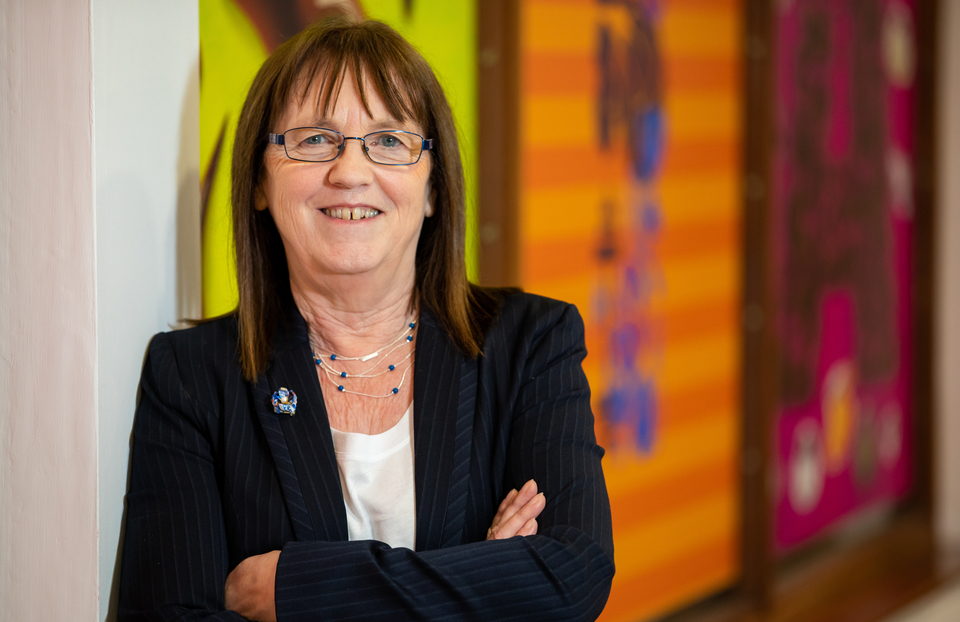 Sheila Porter stands with arms crossed, smiling