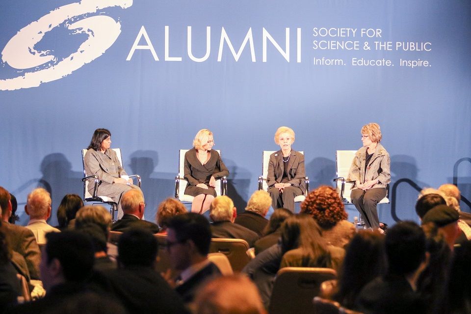 Maya Ajmera, Gayle Wilson and two other women hold a discussion in front of a crowd.