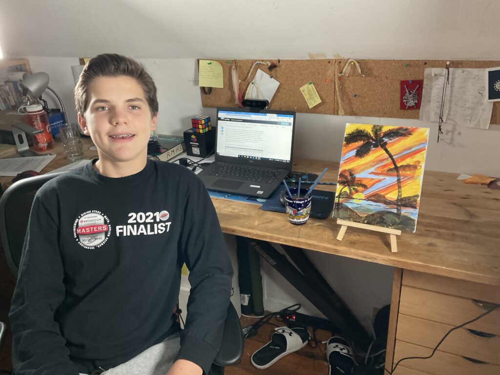 Joseph Simak, a Broadcom MASTERS 2021 alumni, poses in front of his desk with a painting he made during the virtual competition.