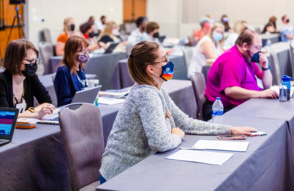 Several teachers listen to a speaker during the 2022 Middle School Research Teachers Conference, held in-person for the first time since 2019.