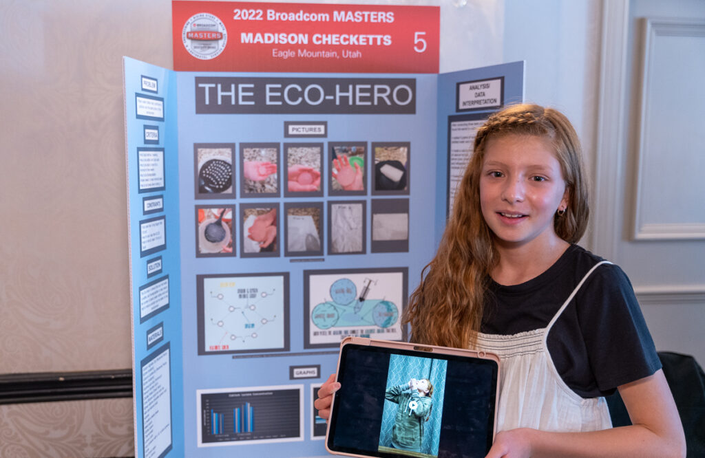 2022 Broadcom MASTERS Finalist Madi Checketts smiles in front of her project board, displaying her research on an edible water bottle that could reduce plastic pollution.