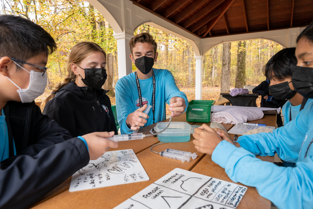 The blue team sits around a table as they design their prototype