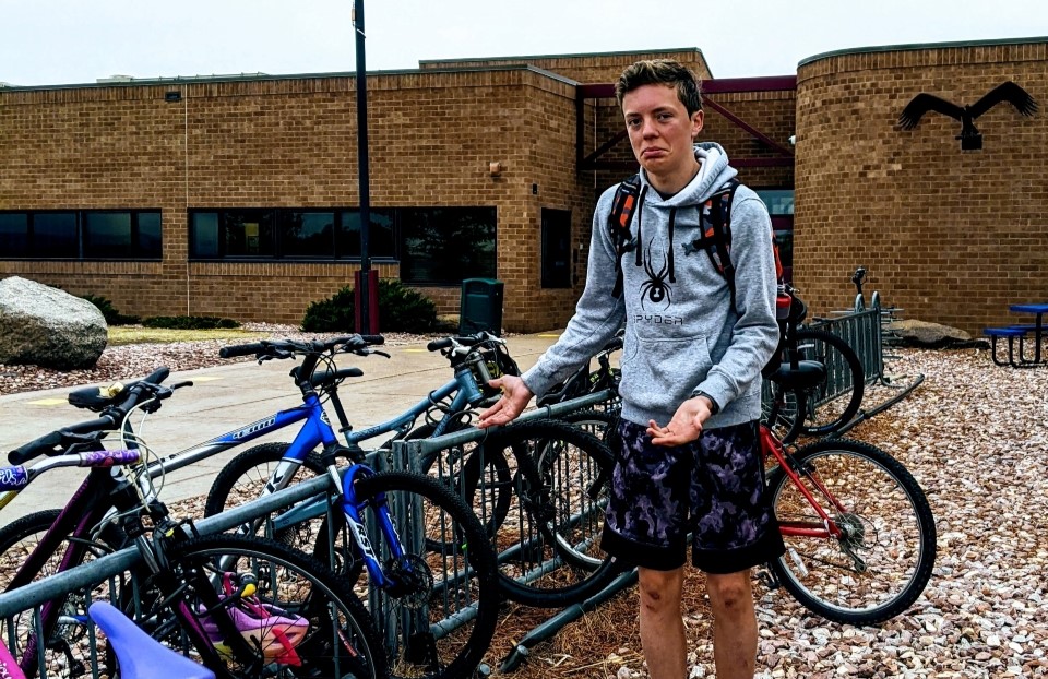 David Kent stands frowning next to the bicycle rack where his bike was stolen