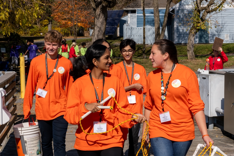 The orange team walking with their rig on the way to testing it over the edge of the dock.