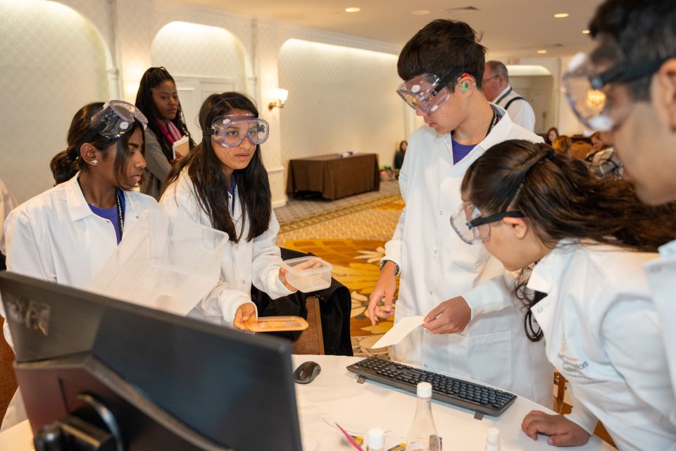 The purple team works together to build a gel electrophoresis chamber.