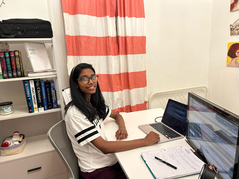 Lehansa poses with her computer and notebook as she works on improving 911 response times using AI.