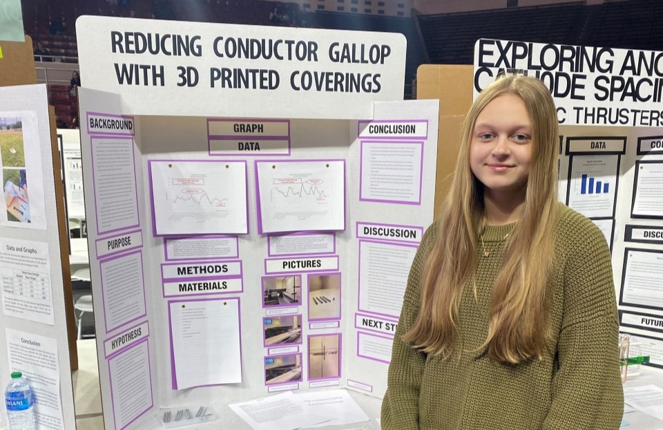Meredith stands with her project poster at a science fair