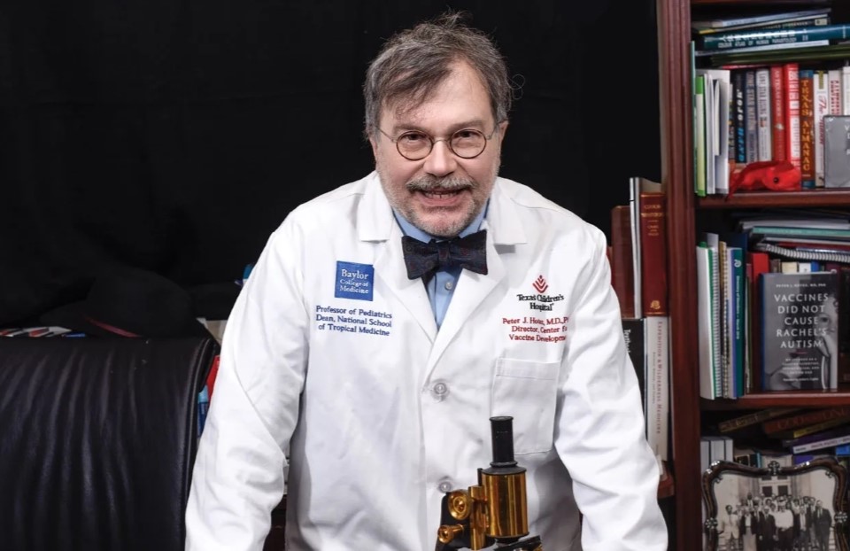 Peter Hotez stands smiling in front of a bookshelf.