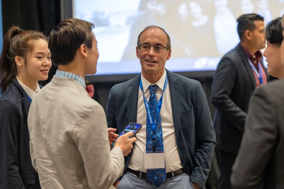 Several finalists speak with a Society for Science alum during the 2023 Regeneron Science Talent Search alumni dinner.