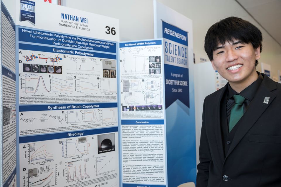 Nathan Wei poses by his poster at the Public Exhibition of Projects.