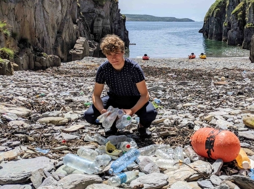 Fionn picks up trash at a beach.