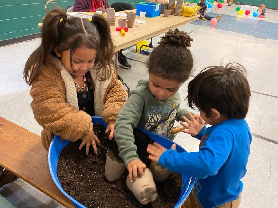 Three young children potting soil as part of Mississippi Delta Nature and Learning Center's programming