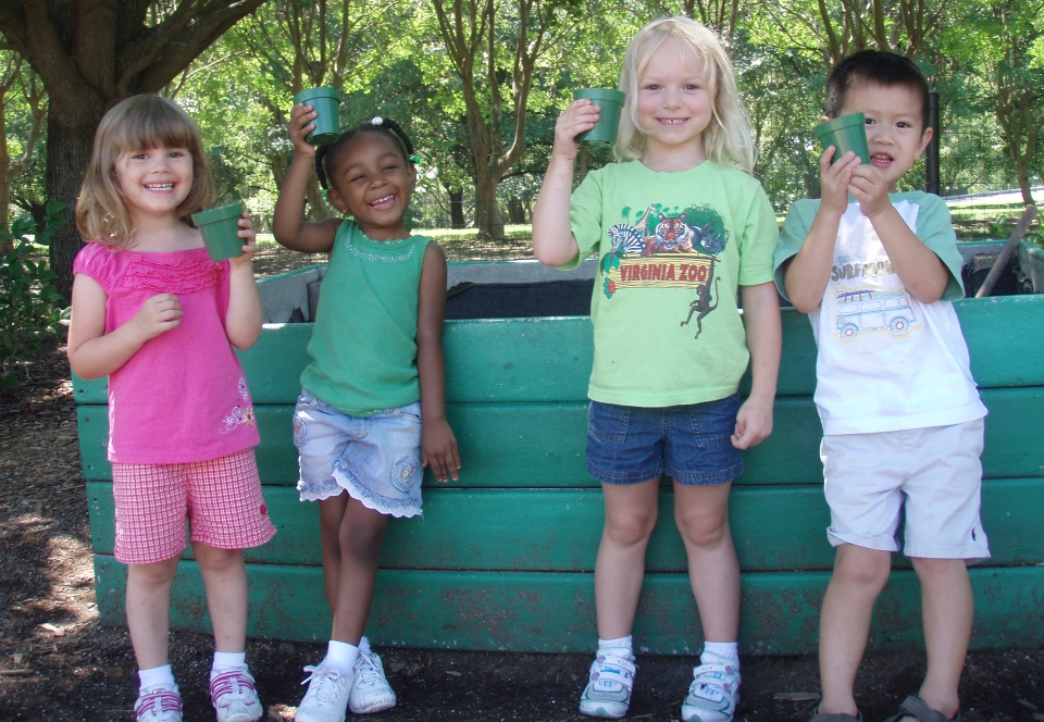 Four children posed in front of an elevated flower bed at Norfolk Botanical Garden