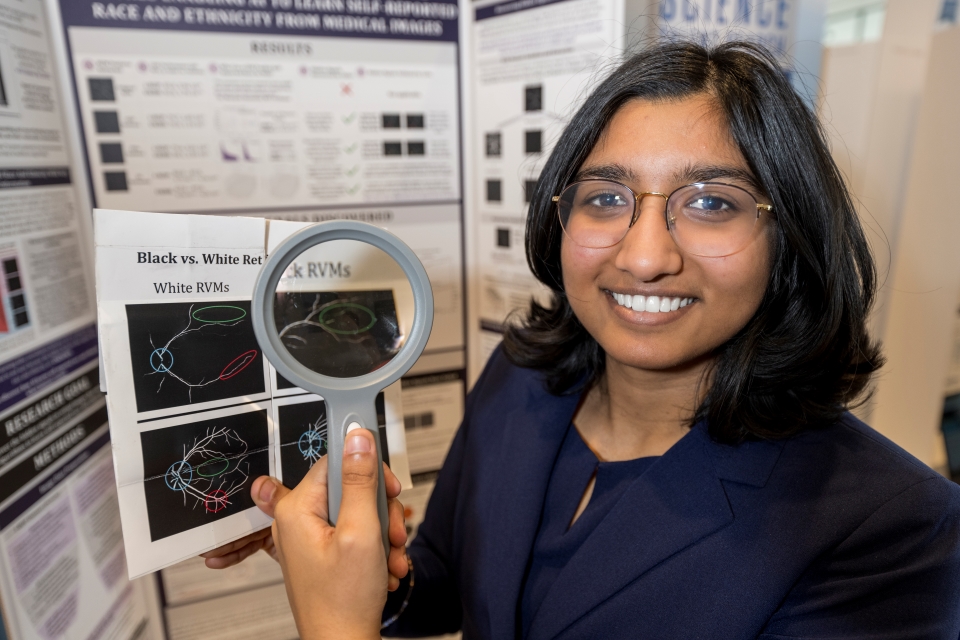 Riya Tyagi standing at her project board.