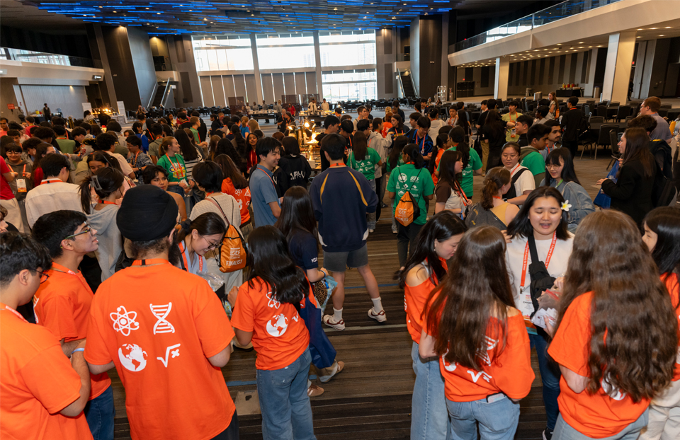 A crowd of 2025 ISEF finalists swarm in the ballroom exchanging pins.