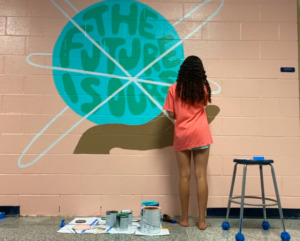 Ava works on painting a mural that says: "The future is ours."