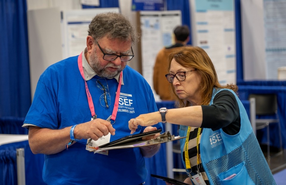 Two volunteers in conversation, referencing clipboard.