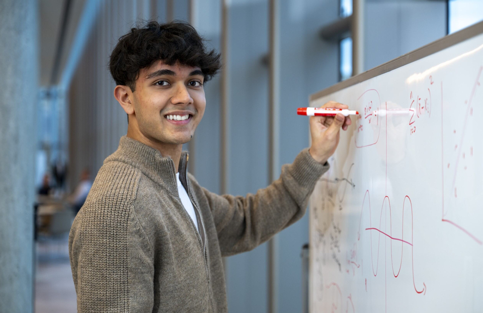 Regeneron STS 2025 finalist Atreya Manaswi drawing on a whiteboard.