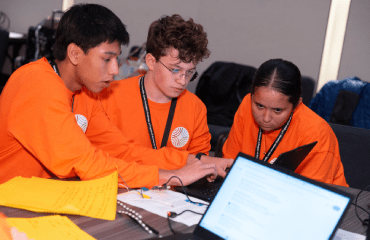 Three JIC 2025 Finalists using a Micro:bit in a team challenge.