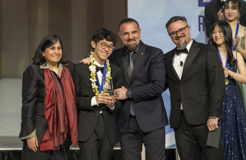 Regeneron STS 2025 Finalist Logan Lee receiving his 4th Place Award on stage with Maya Ajmera of Society for Science, George Yancopoulos of Regeneron, and Jason Valentine, STS Judging Chair.
