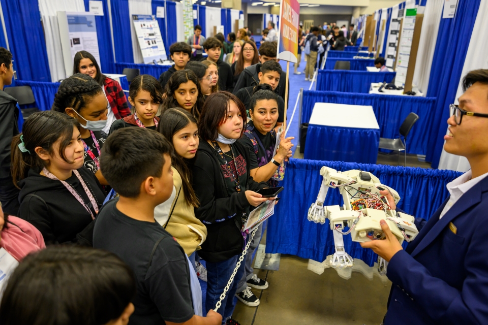 An finalist presenting his research to younger students at Education Outreach Day at Regeneron ISEF, in 2023.