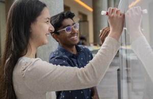 Regeneron STS 2025 finalists Rivka Lipkovitz and Akilan Sankaran drawing on a whiteboard.