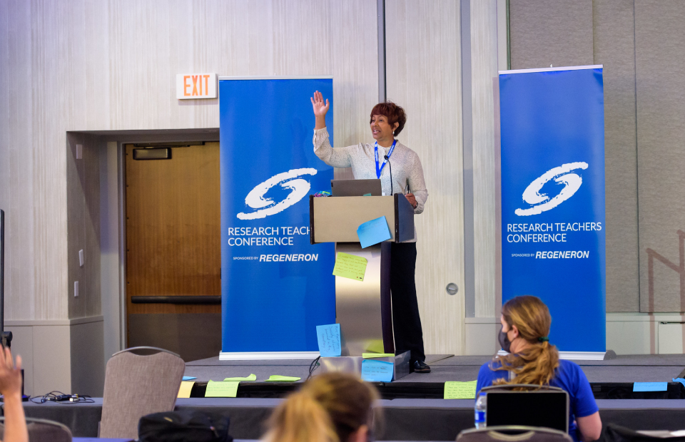 A woman speaking at a podium at the 2021 High School Research Teachers Conference.