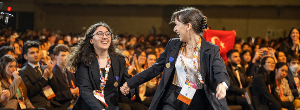 Two finalists running toward the stage at the Regeneron ISEF 2023 awards ceremony