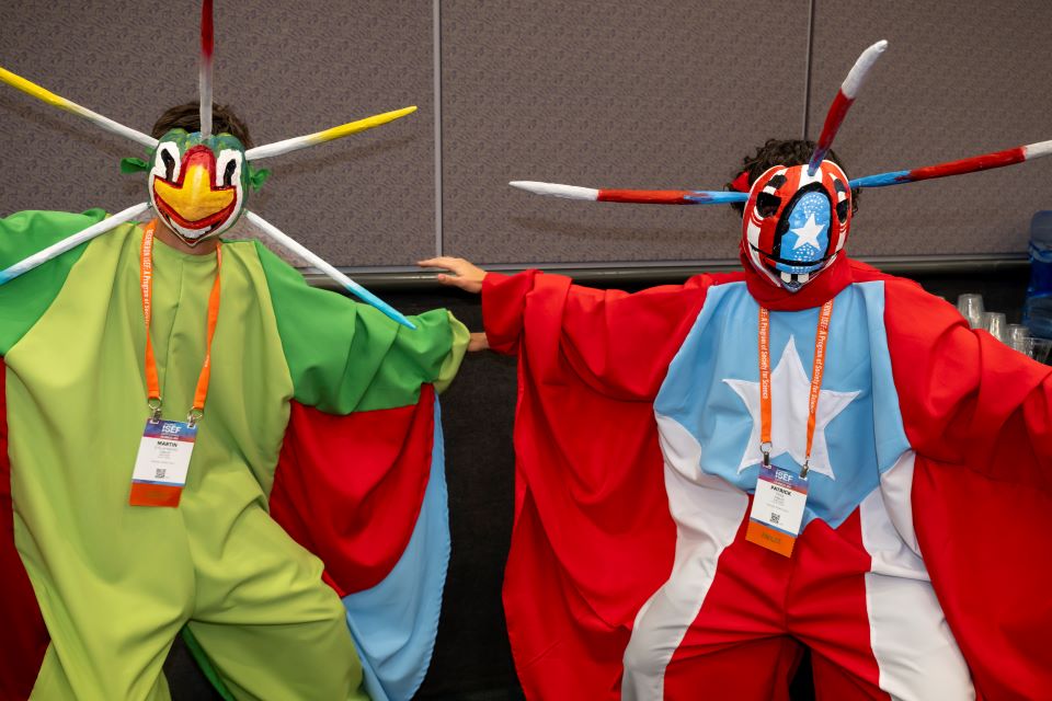 2024 ISEF - Two finalists in colorful outfits and masks pose at the pin exchange.