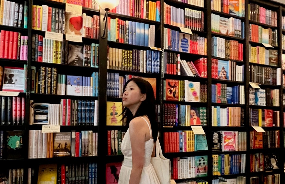 Regeneron STS finalist Angeline Zhao next to a large wall of books.