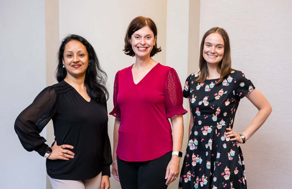 Three women posed for a photo wearing a black, red and cupcake dress.
