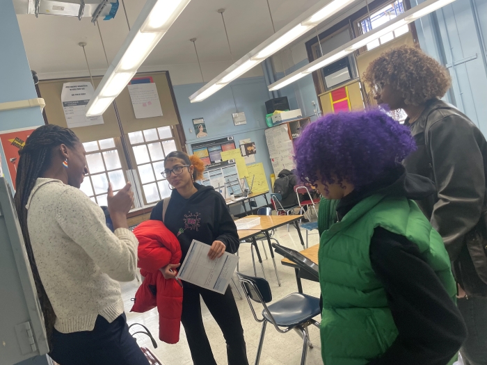 A scientist speaks after class with three students.