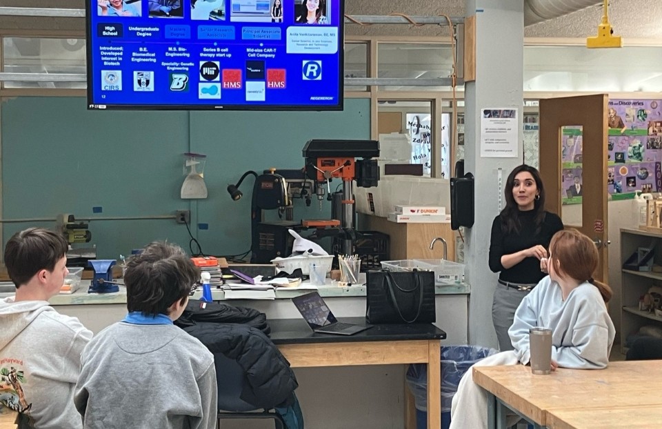 A scientist presents in front of a classroom full of students