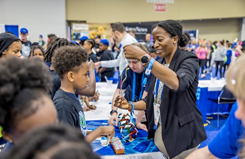 A volunteer leads a student in a hands-on activity