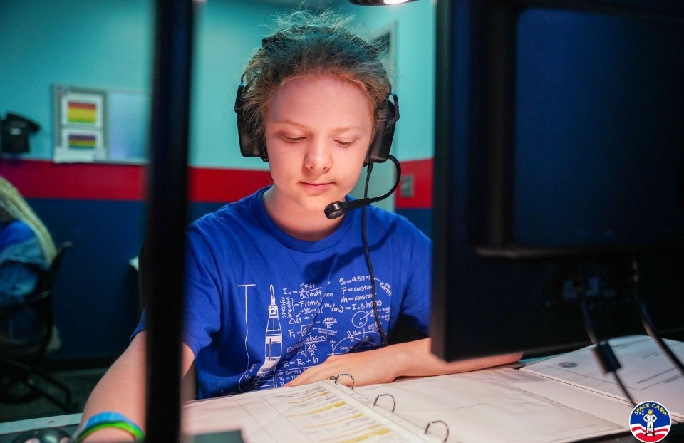 Ezekiel Wheeler wearing a headset as he works on a mission at Space Academy